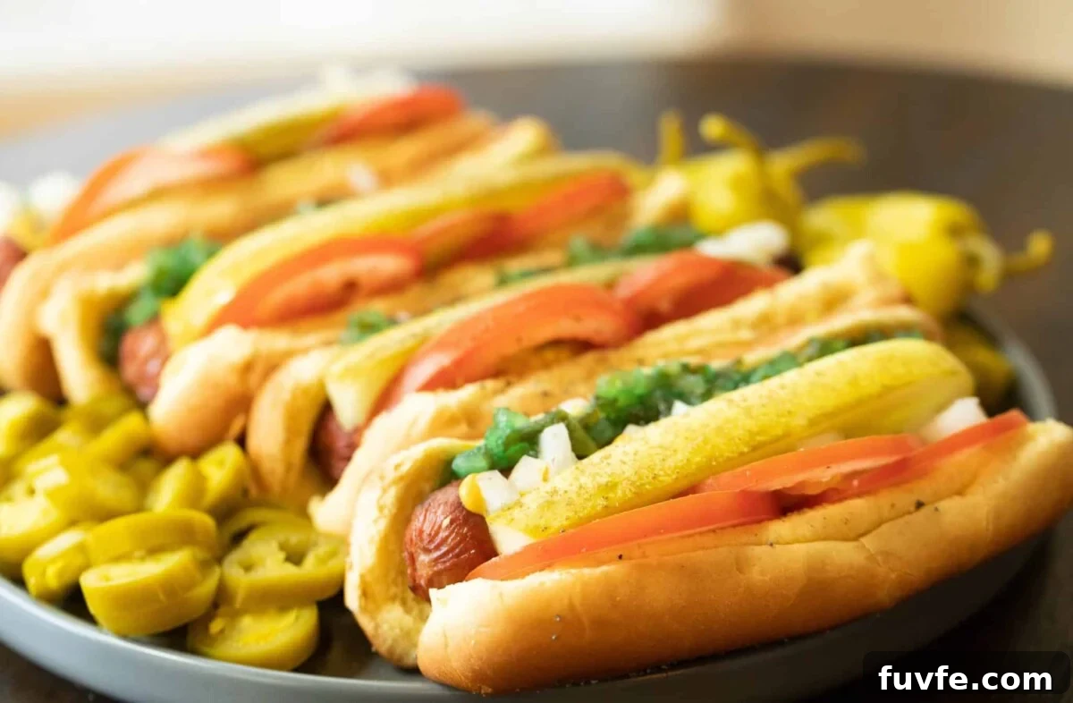 Cooked frankfurters on buns topped with sliced tomatoes, pickles, and relish.