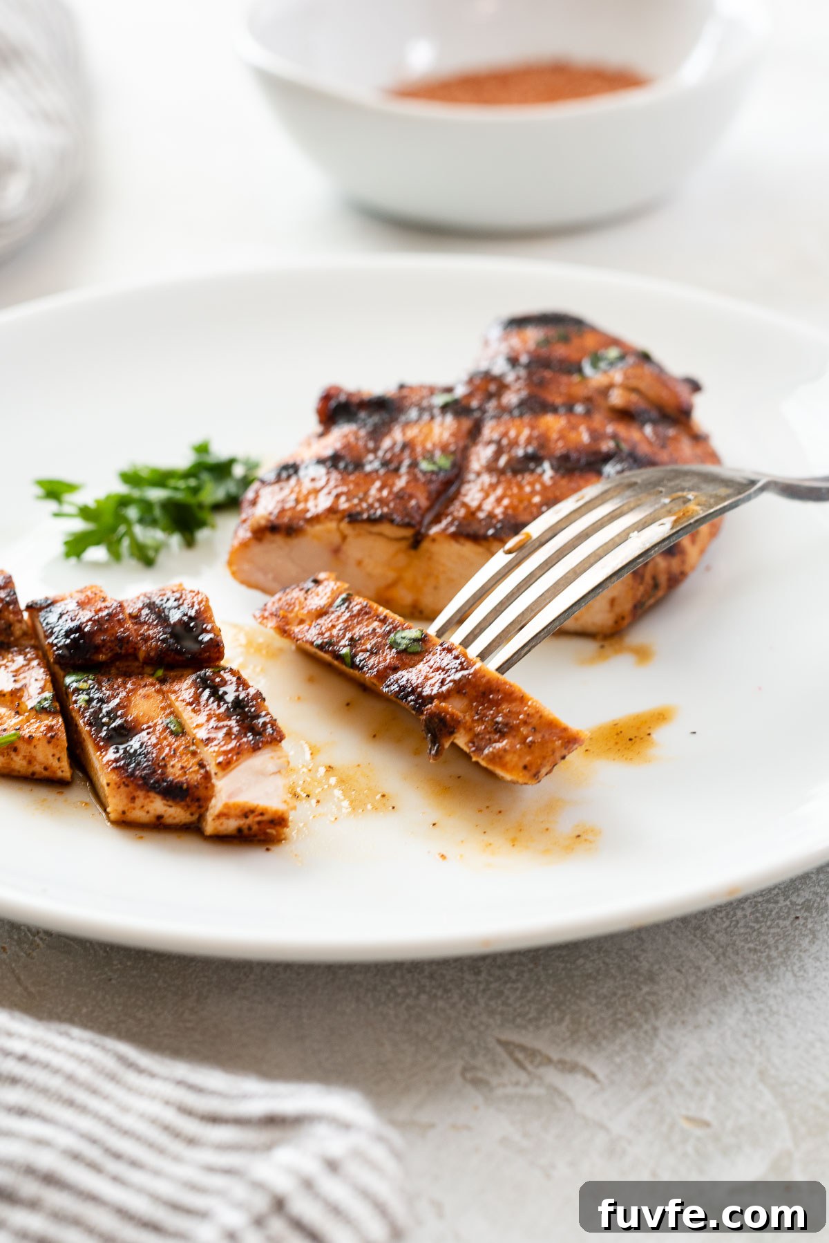Slice of grilled chicken with bbq rub on fork