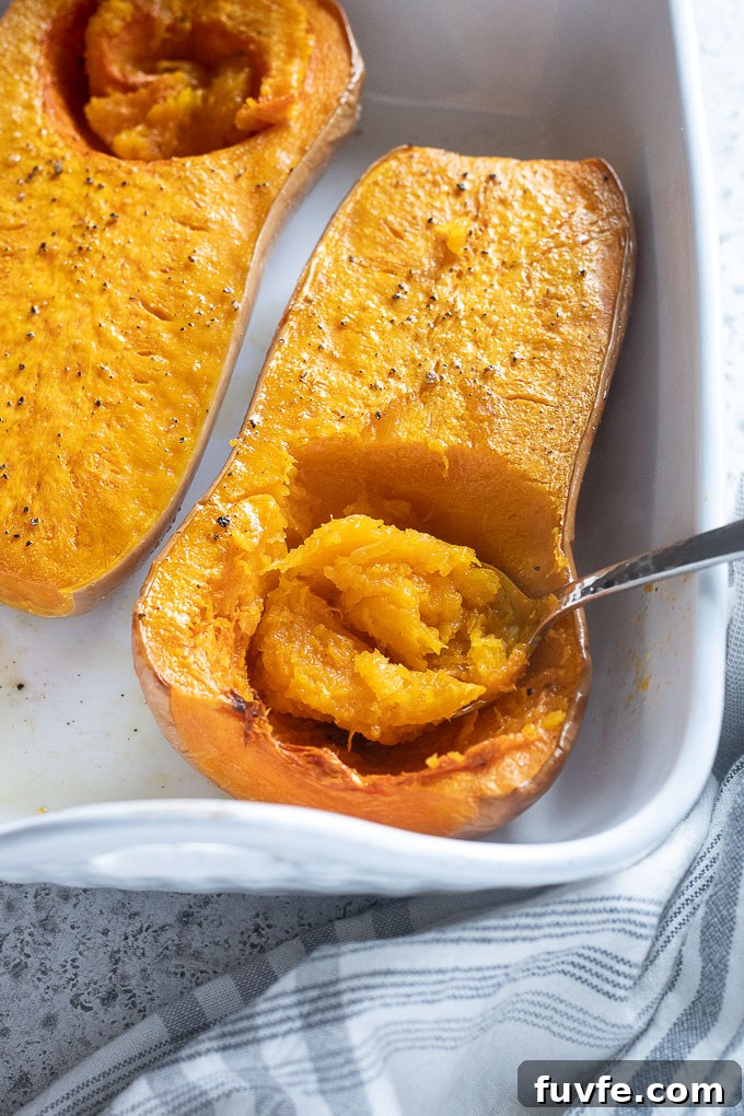 Spoon scooping flesh out of whole roasted butternut squash