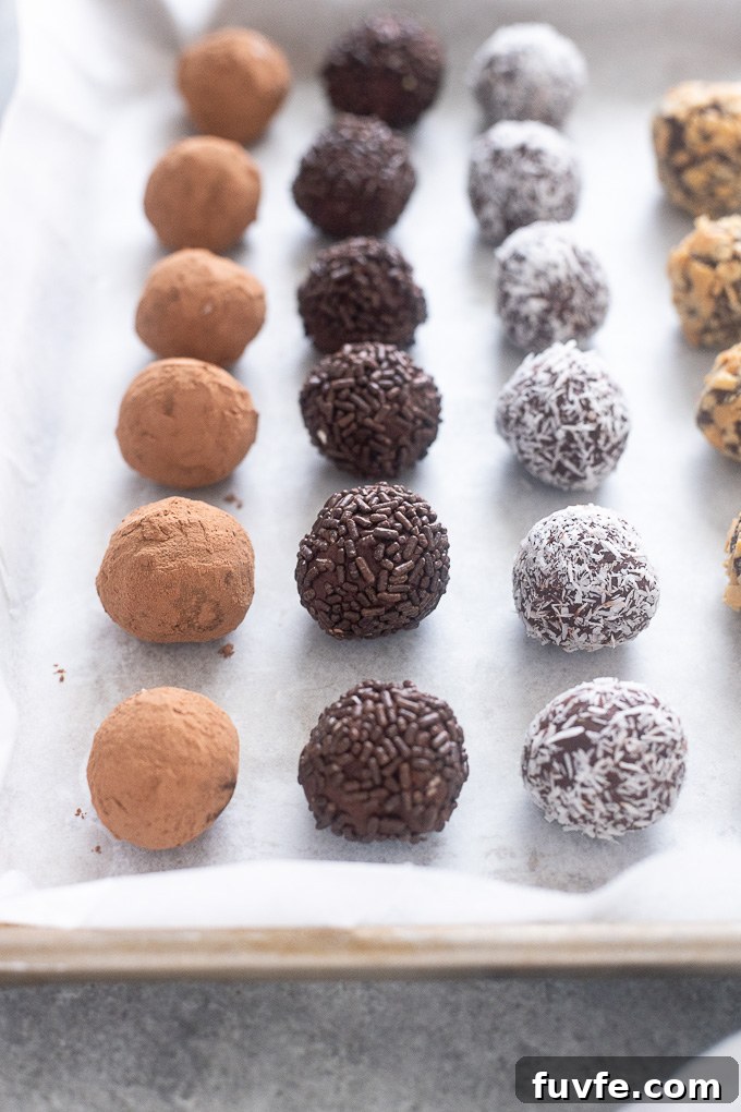 Dark chocolate truffles rolled in coatings on a baking sheet