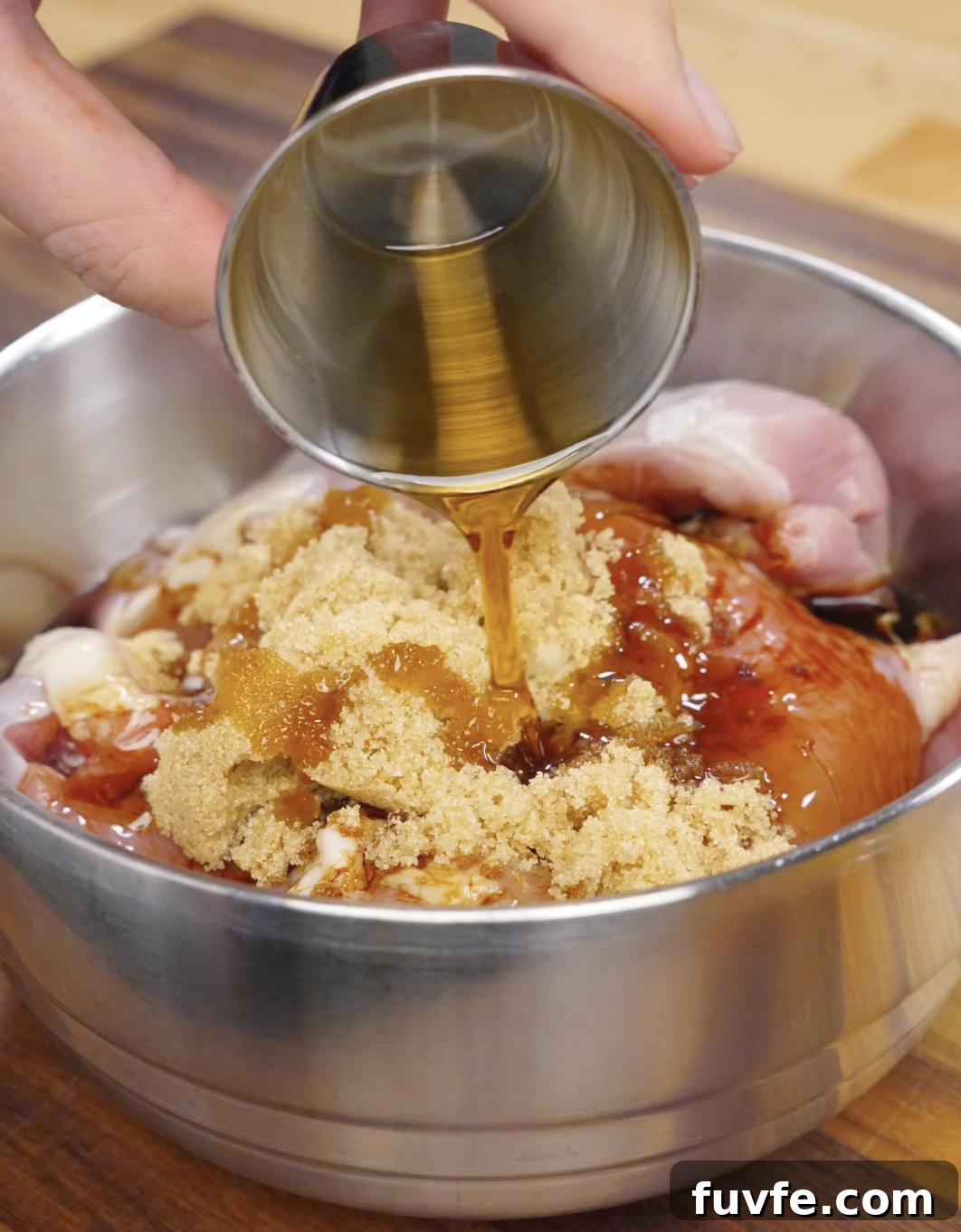 Honey being poured over chicken thighs in a bowl with soy sauce, gochujang, garlic, and brown sugar to create a sweet and savory Korean bulgogi marinade.