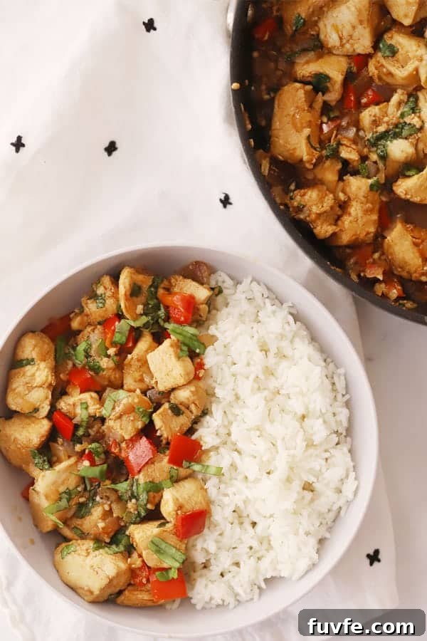 Garlic Basil Chicken Stir-Fry with Crispy Vegetables 4 A serving bowl filled with white rice and thai chicken and basil stir fry.