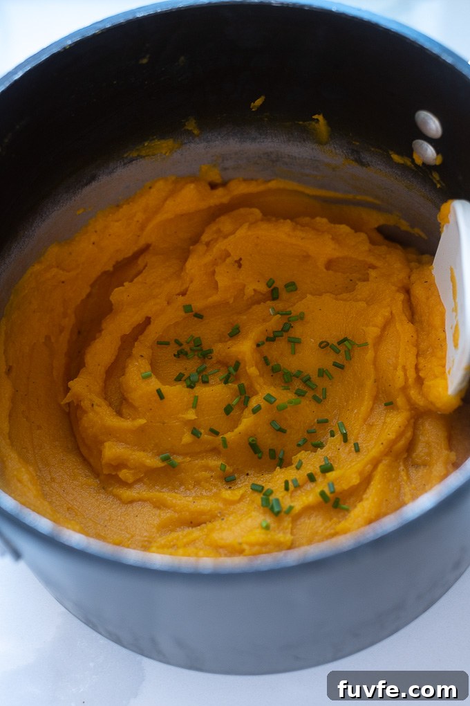 Mashed butternut squash in a pot with chives on top