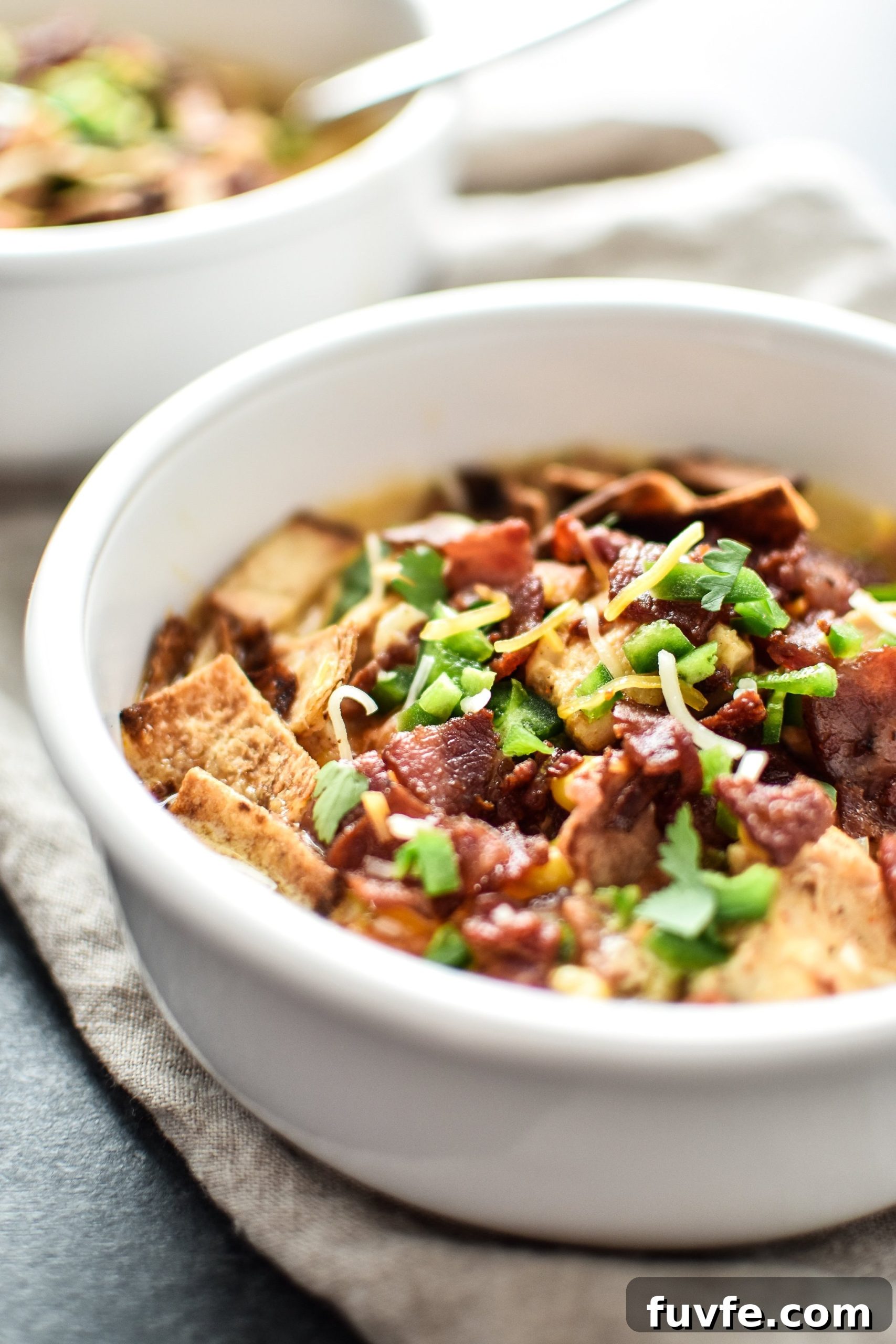 Instant Pot Jalapeño Popper Chicken Soup Recipe 5 A bowl of jalapeno popper chicken soup from the side with toppings.