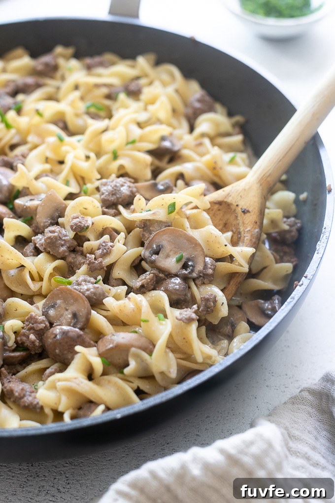 Wooden spoon digging into one pot hamburger stroganoff