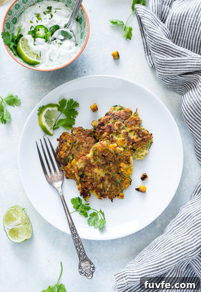 How to Make Crispy Zucchini Fritters 7 Zucchini and corn fritters on a plate with yogurt alongside