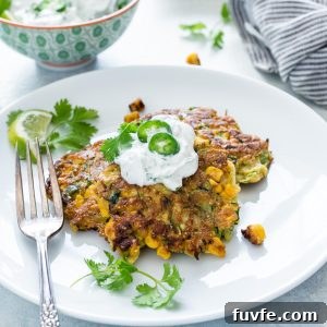 How to Make Crispy Zucchini Fritters 8 zucchini fritters on a plate topped with yogurt