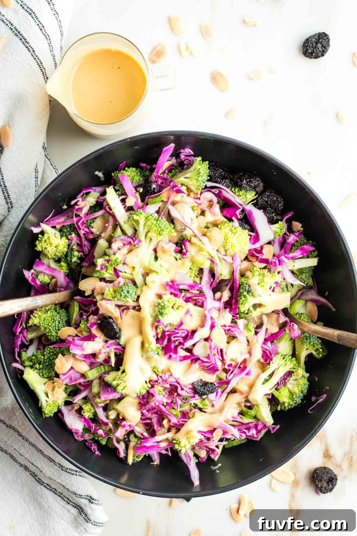 Brightly colored broccoli and cabbage with a orangish creamy dressing, sprinkled with almonds and dried cherries.