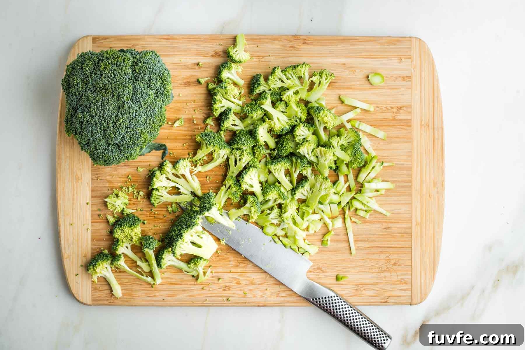 Trimming broccoli stalks into florets and pieces of the stems.