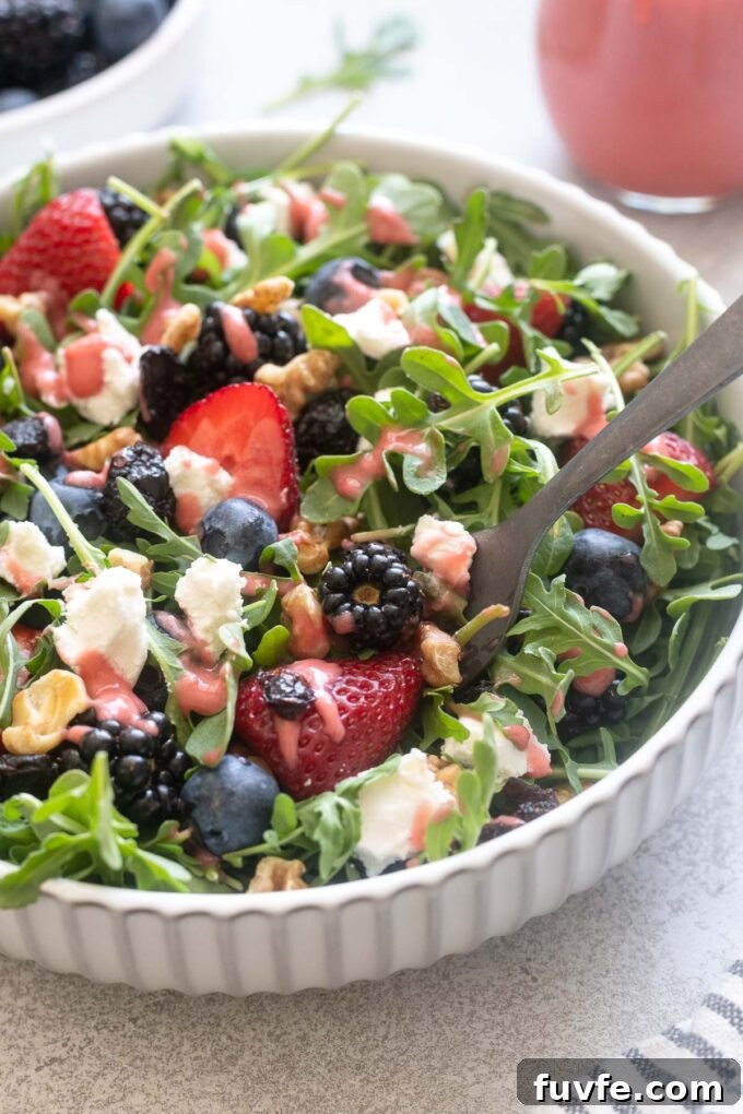 Fresh Berry and Arugula Salad Recipe with Goat Cheese 2 Berry arugula salad with goat cheese in a bowl with a fork digging in.