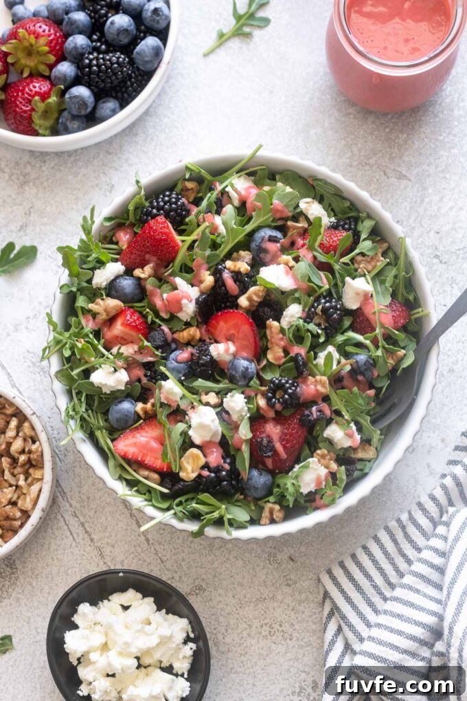 Fresh Berry and Arugula Salad Recipe with Goat Cheese 5 Summer arugula salad in a bowl with a serving spoon.