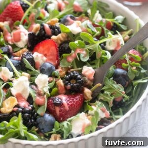 Fresh Berry and Arugula Salad Recipe with Goat Cheese 7 Berry arugula salad with goat cheese in a bowl with a fork digging in.