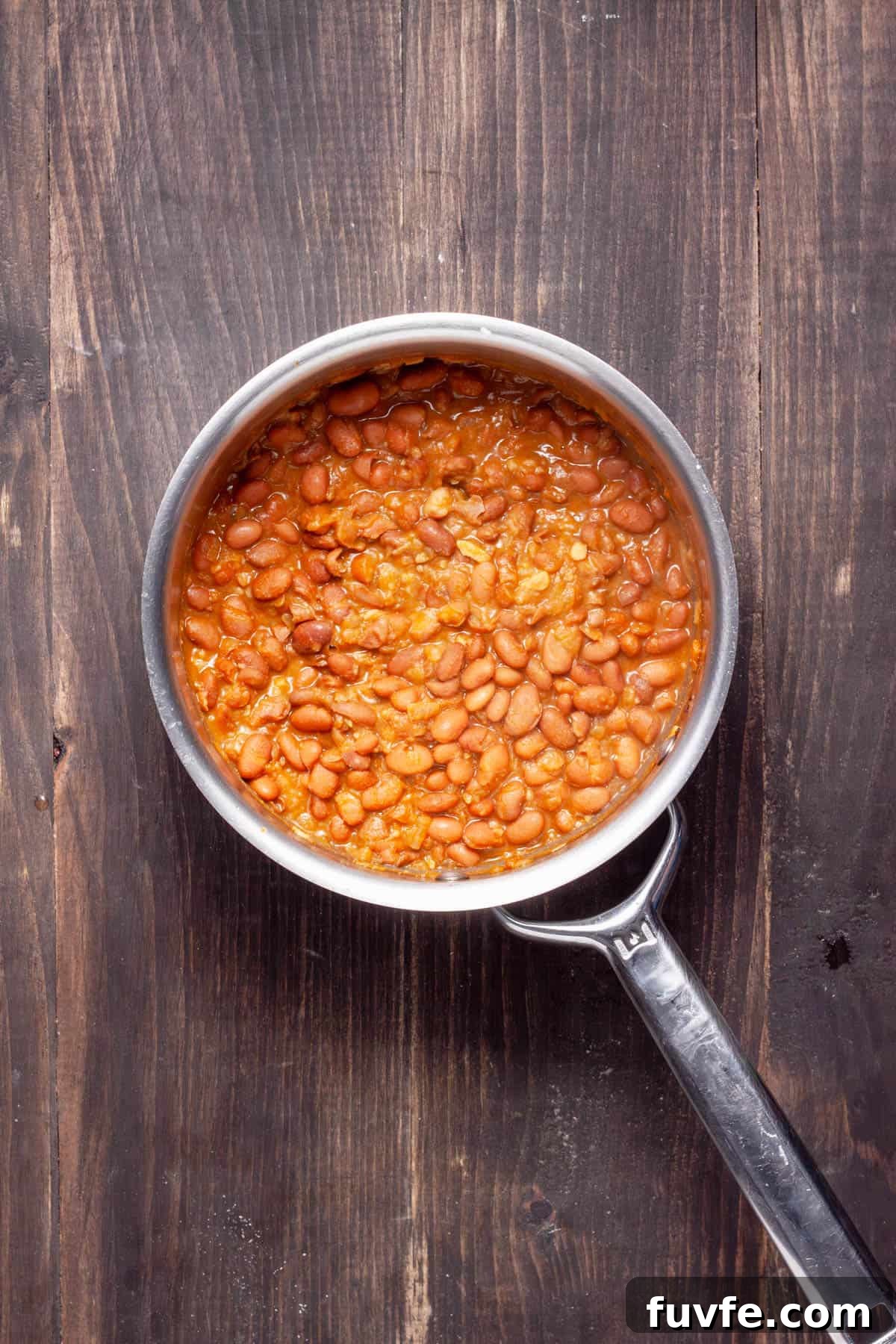 Vegan refried beans cooking in a medium saucepan ready to get mashed.
