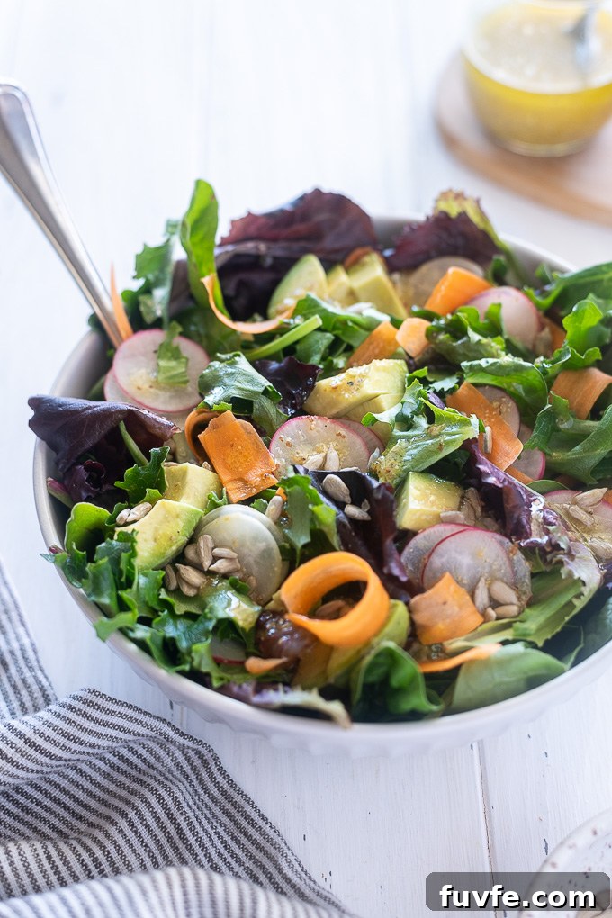 Bowl of spring mix salad with salad servers digging in