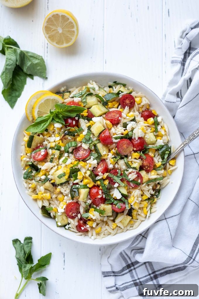 Lemon orzo pasta salad in a white bowl with basil on top