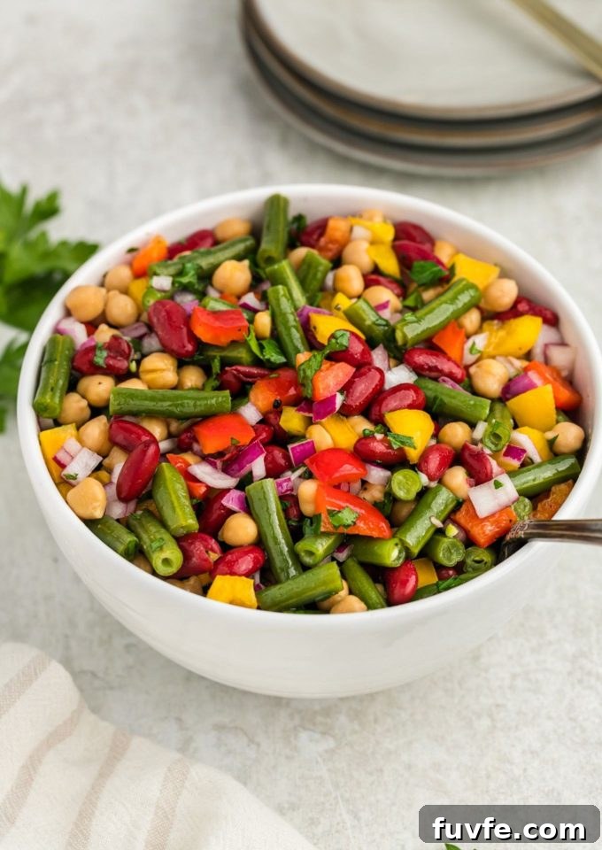 Three bean salad in white bowl with spoon inside