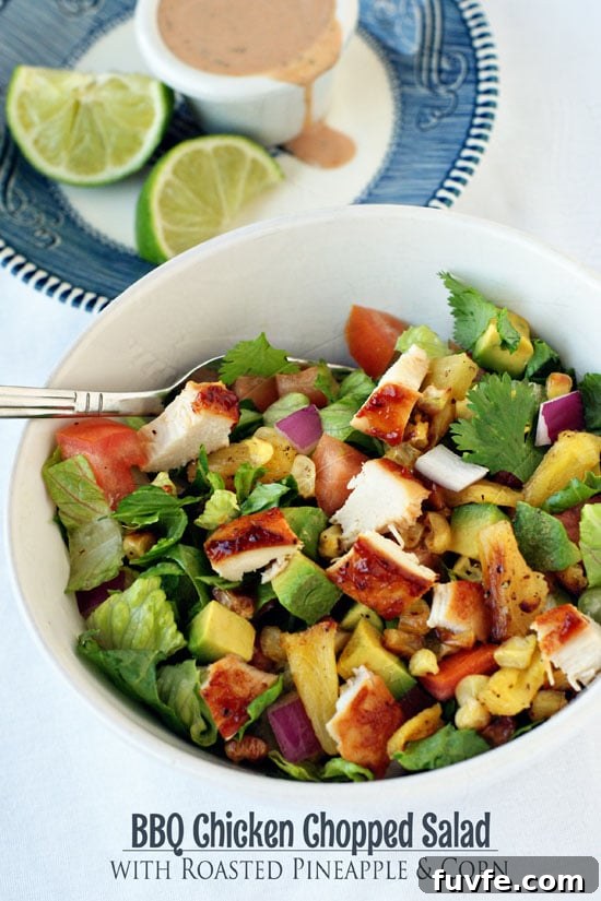 Healthy BBQ Chicken Chopped Salad in a large white bowl with a silver fork on a white table.