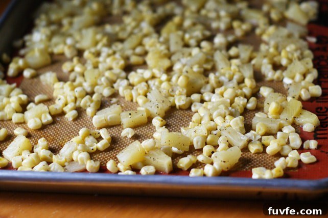 Roasting pineapples and corn on a lined baking sheet.