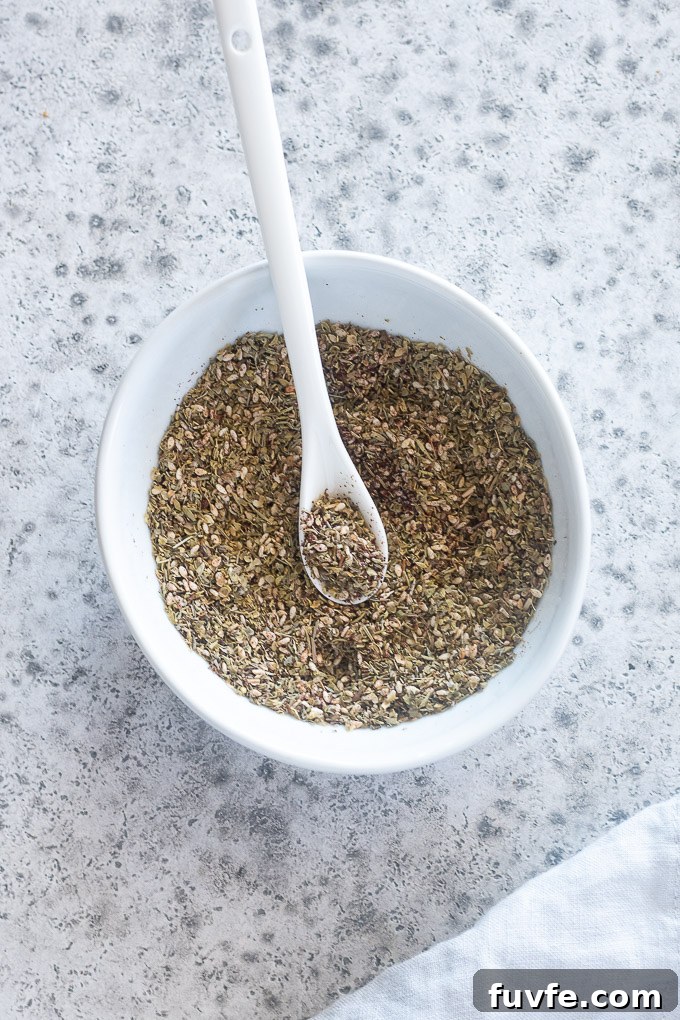 Za'atar spice in a white bowl with a spoon
