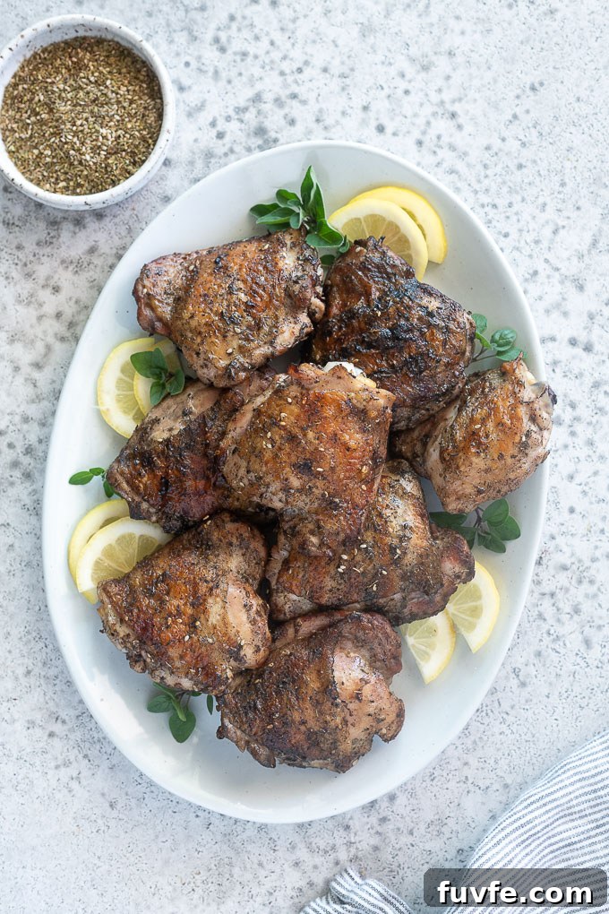 Juicy Grilled Chicken Thighs with Crispy Skin 8 Grilled chicken thighs on a platter with lemon and oregano