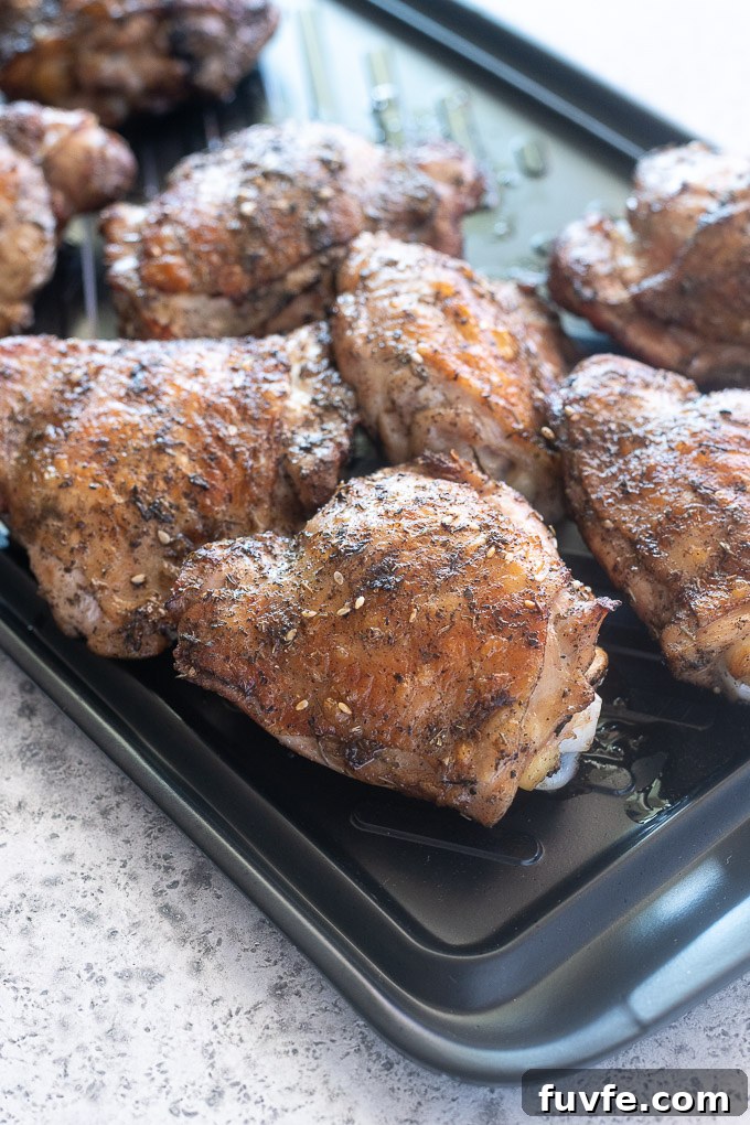 Juicy Grilled Chicken Thighs with Crispy Skin 5 Grilled chicken thighs on a black tray fresh from the grill