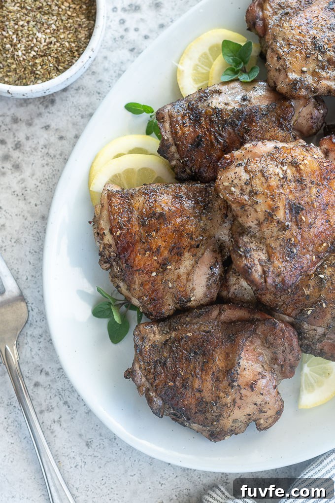 Juicy Grilled Chicken Thighs with Crispy Skin 6 Grilled chicken thighs piled on a platter with lemon and oregano