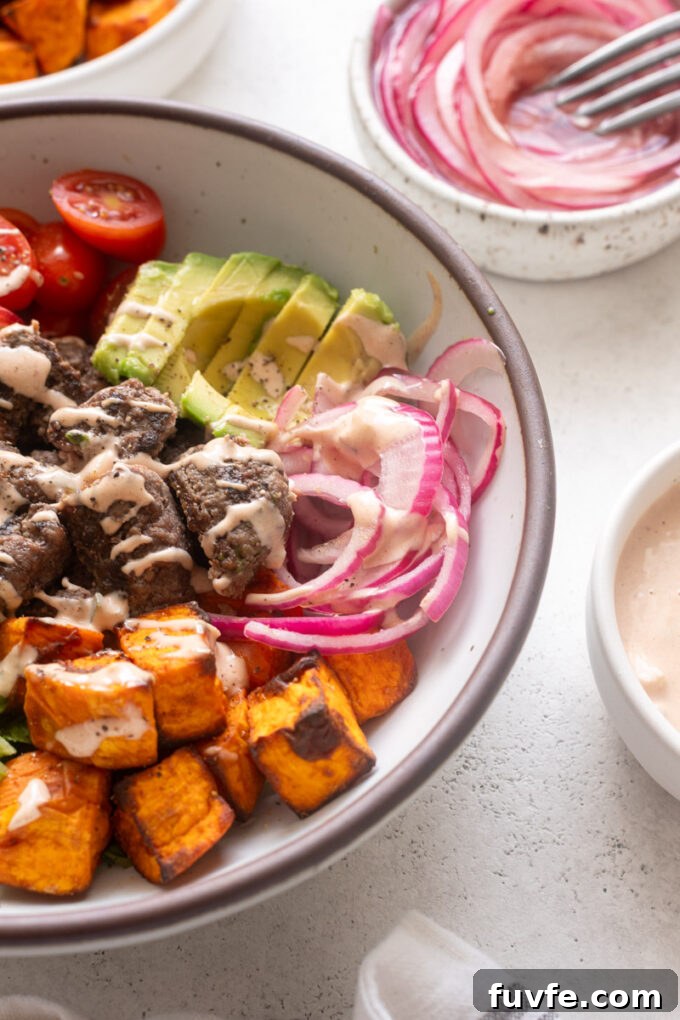 Close-up burger bowl with burger sauce, avocado and pickled onions.