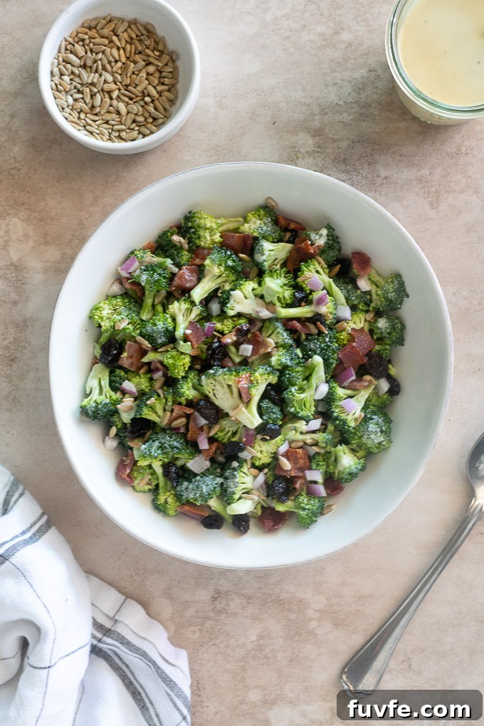 Crunchy Broccoli Salad with Bacon and Creamy Dressing 3 Broccoli salad recipe with bacon in a white bowl with a spoon alongside