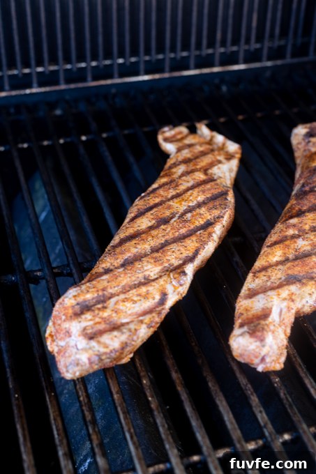 Pork tenderloins cooking on gas grill.