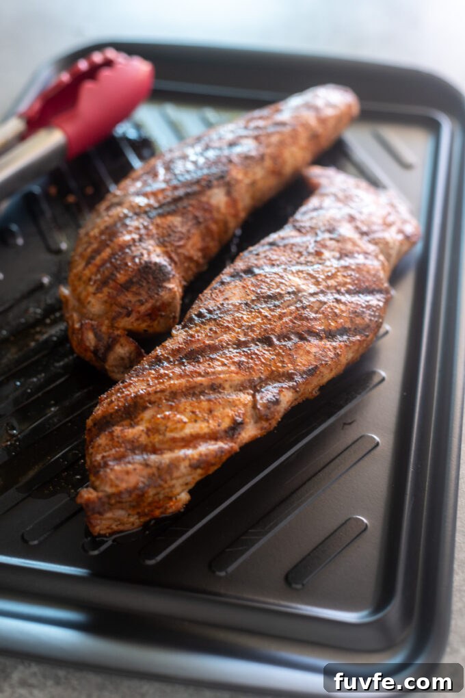 Spice rubbed grilled pork tenderloin on a cutting board.