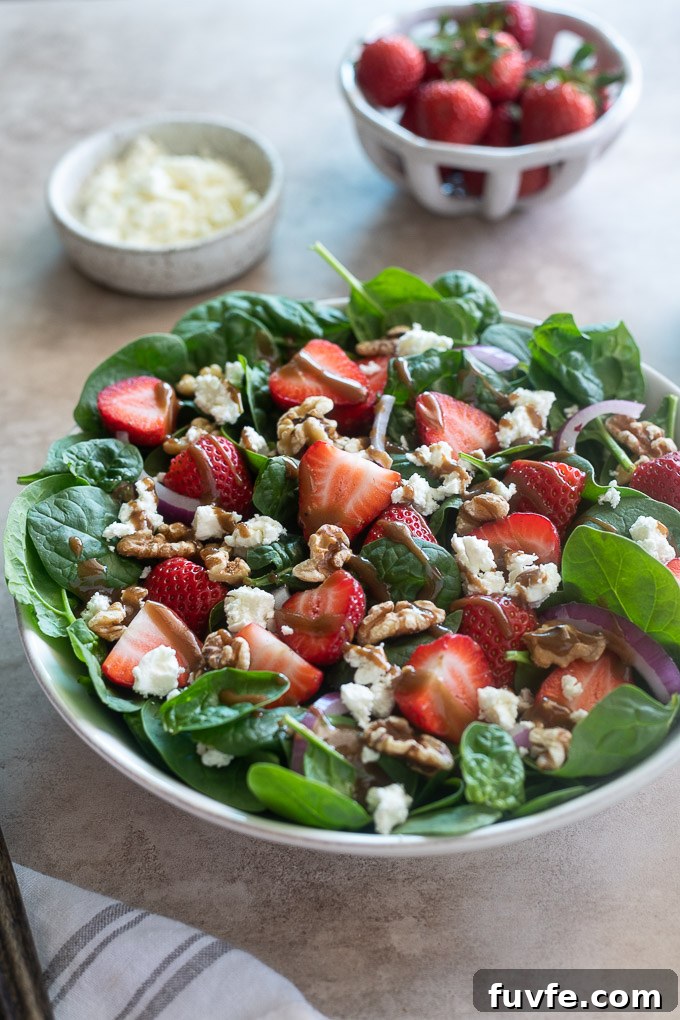 Spinach and strawberry salad in a white serving bowl