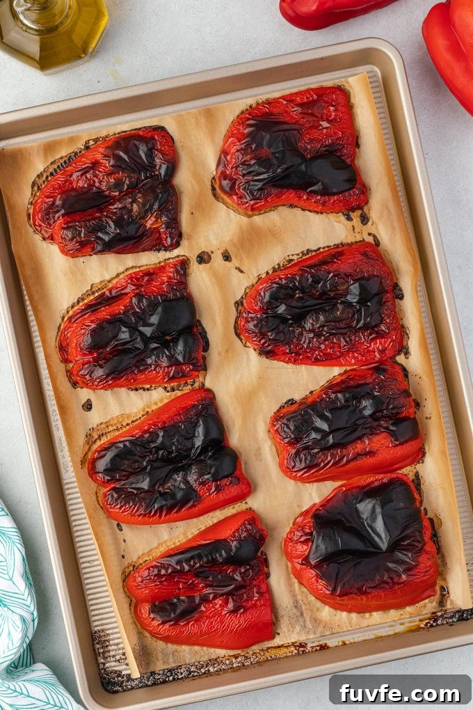 Roasted bell peppers on a parchment lined baking sheet