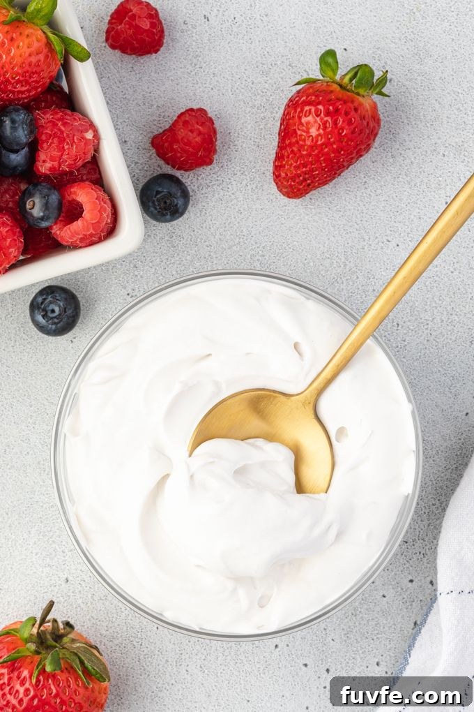 Whipped coconut cream in a bowl surrounded by berries.