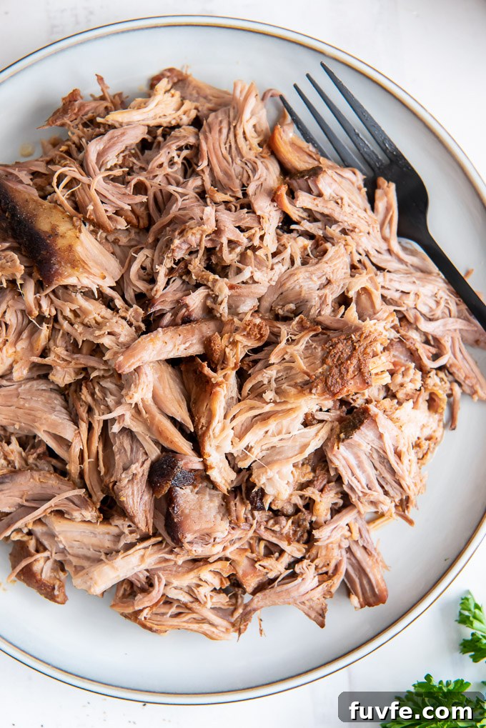 Slow cooker pulled pork on a white plate with a fork