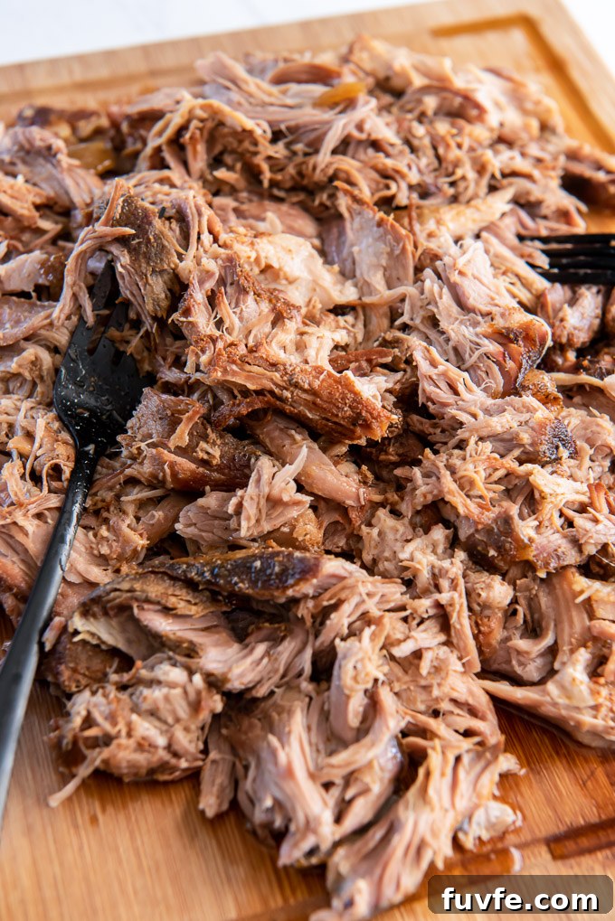 Slow cooker pulled pork shredded with forks on a cutting board