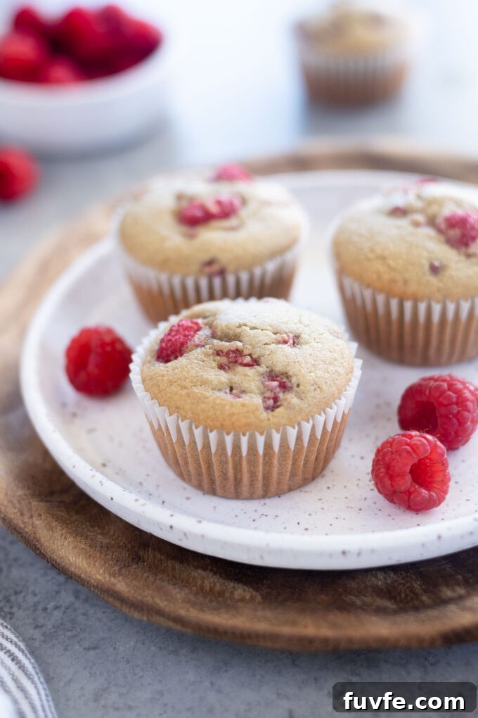 Three gluten free raspberry muffins on a white plate