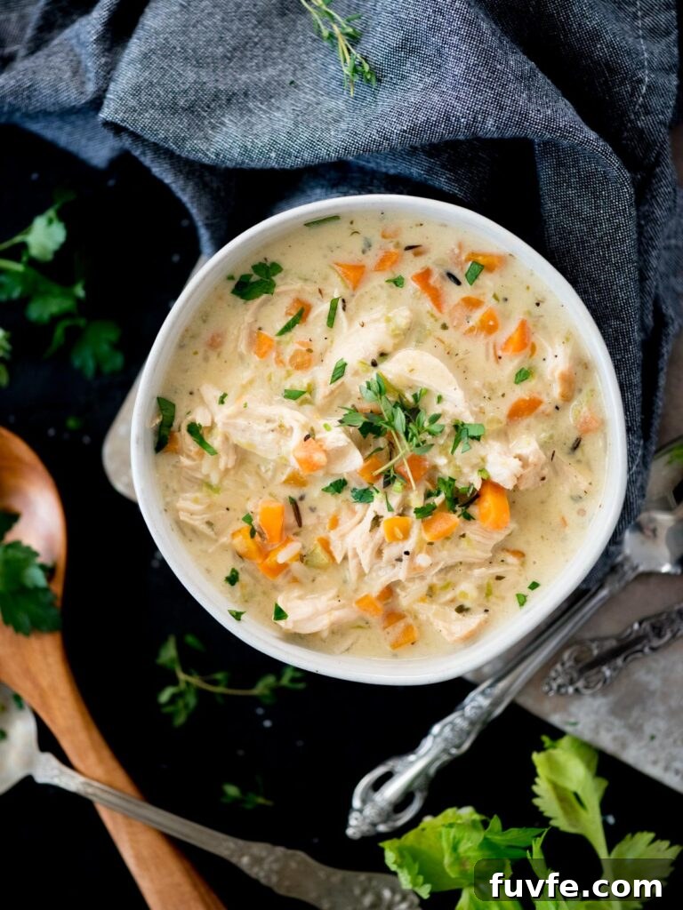 Creamy Chicken and Wild Rice Soup Recipe for Comforting Weeknights 2 Creamy chicken and rice soup in a bowl topped with parsley and thyme