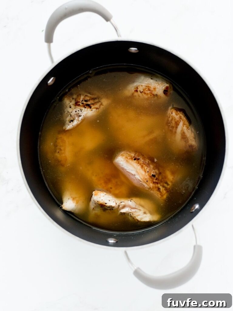 Creamy Chicken and Wild Rice Soup Recipe for Comforting Weeknights 5 chicken and broth in soup pot