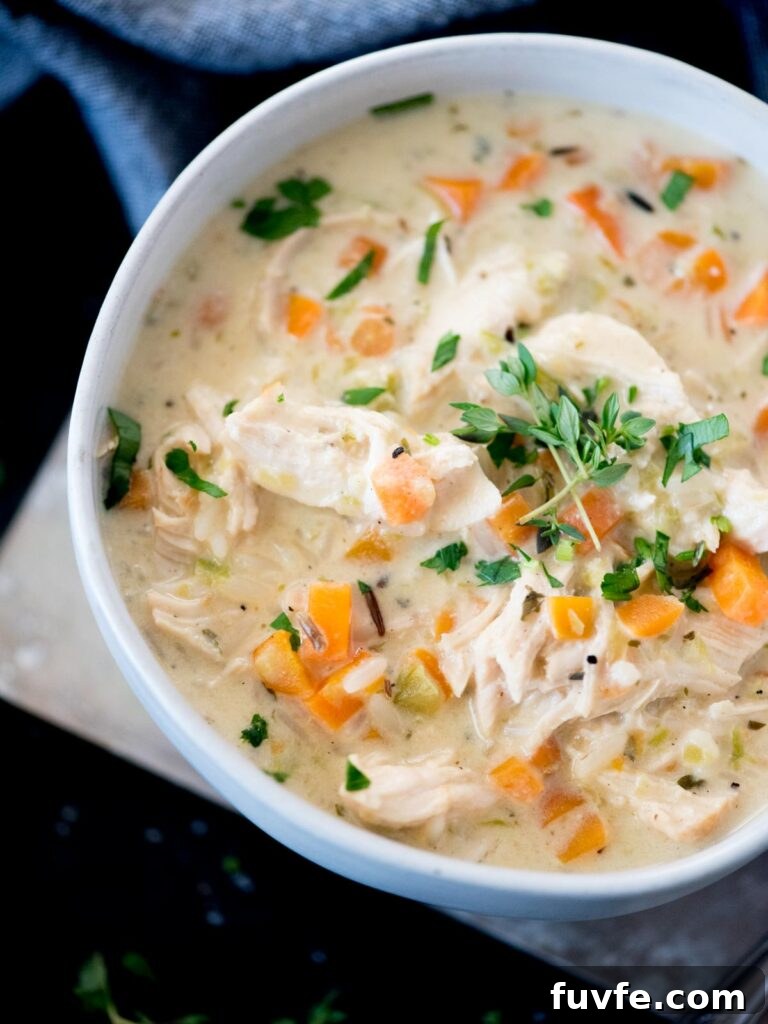 Creamy Chicken and Wild Rice Soup Recipe for Comforting Weeknights 10 Creamy chicken and rice soup in a bowl topped with parsley and thyme