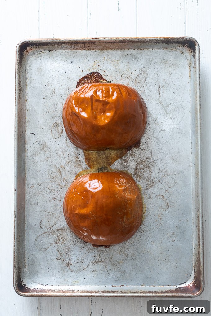Roasted pumpkin halves cut side down on baking sheet