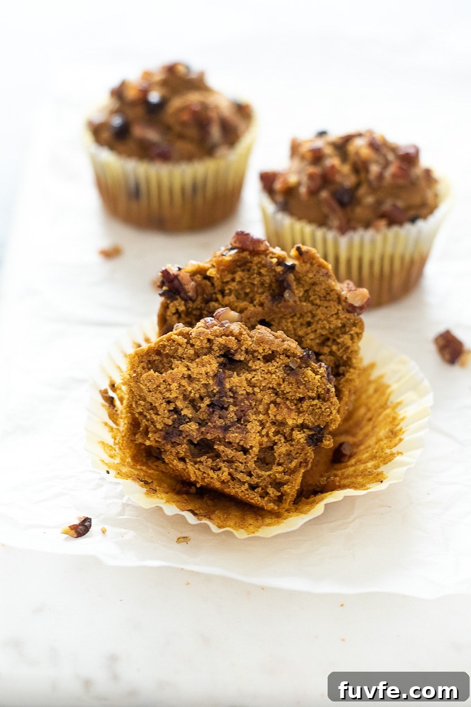 Pumpkin oat flour muffins with front muffin cut in half.