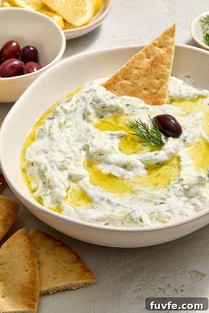 Authentic Greek Tzatziki: Creamy Cucumber-Yogurt Sauce 6 Greek tzatziki in a bowl with pita bread dipped in.
