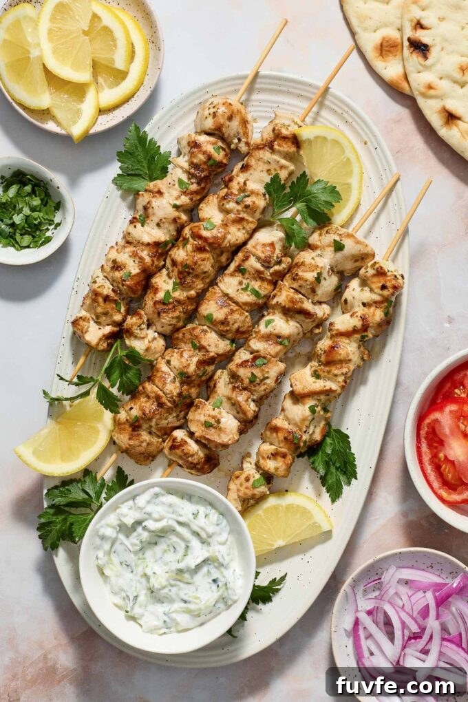 Authentic Greek Chicken Souvlaki Recipe with Tzatziki 2 Greek chicken souvlaki on a platter with tzatziki sauce.
