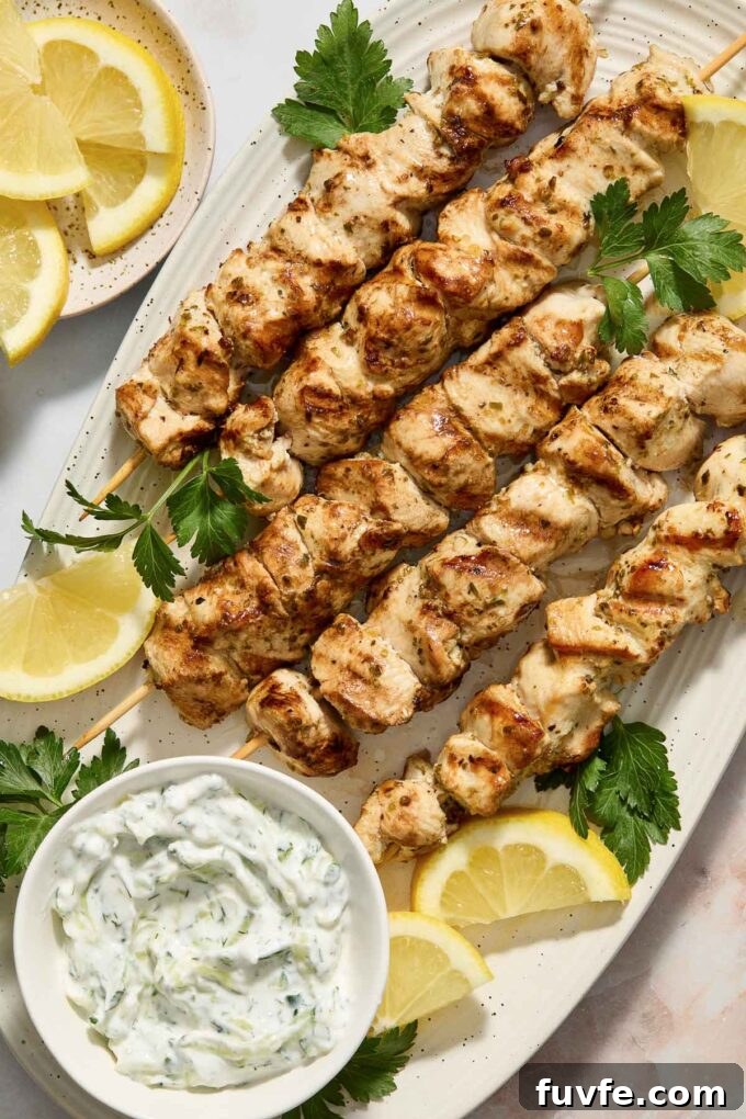 Authentic Greek Chicken Souvlaki Recipe with Tzatziki 5 Chicken souvlaki on skewers with Greek tzatziki and lemon wedges.