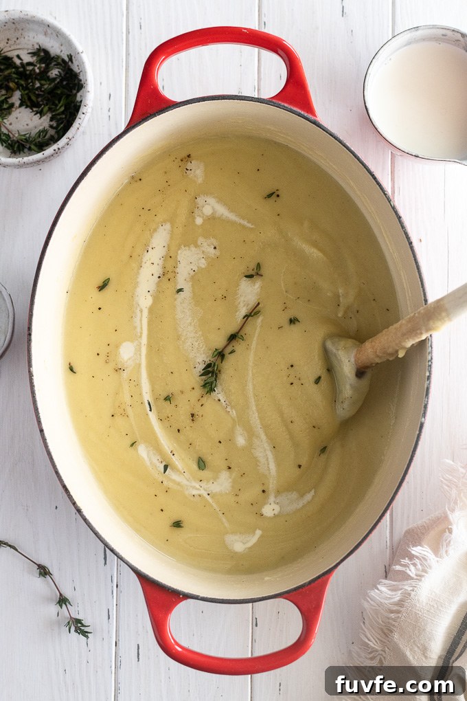 Creamy Roasted Parsnip Soup with Thyme 3 Parsnip soup in a dutch oven with a thyme sprig and wooden spoon