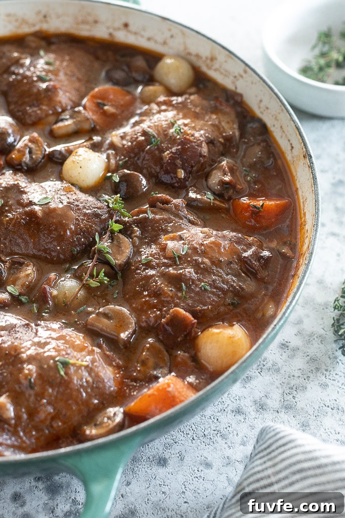 Classic Coq au Vin Recipe: French Red Wine Braised Chicken 6 traditional coq au vin in a Dutch oven with thyme sprigs