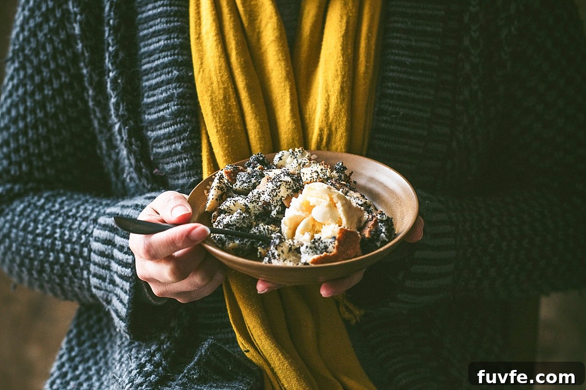 A woman holding a bowl of Mákos Guba (Hungarian Bread Pudding) in a brown decorative bowl