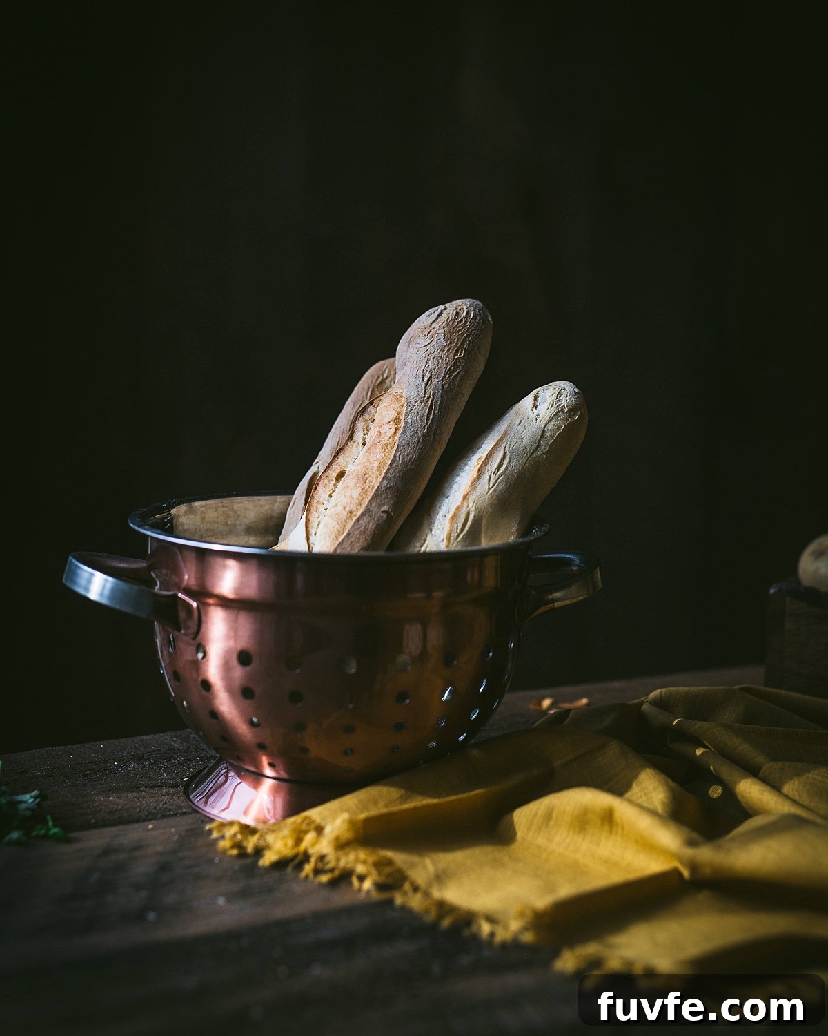 bread for makos guba in a copper colander on a wooden table with a mustard yellow cloth