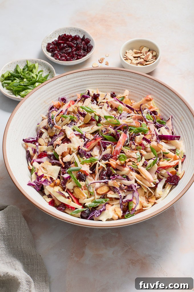 Apple and fennel slaw in a bowl with garnishes surrounding