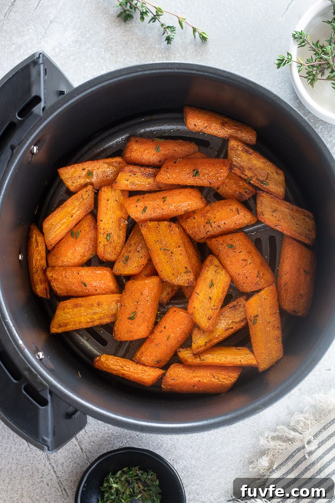 Roast carrots in air fryer garnished with fresh thyme leaves.
